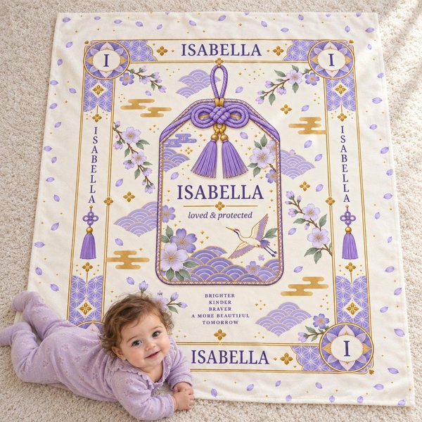 Personalized baby name blanket with a lavender omamori charm design and the sample name Isabella, with a baby lying on her tummy beside it, a custom Japanese-inspired newborn gift.