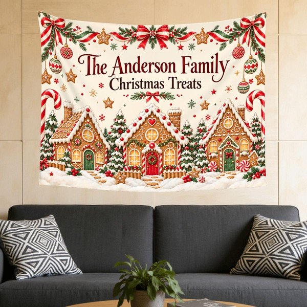 Personalized Christmas tapestry above a gray sofa: gingerbread house village with candy canes, ribbons and ornaments under the sample title The Anderson Family Christmas Treats, a cozy living room Christmas wall decor idea.